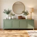 Wide view of a sage green painted buffet in a sunlit modern dining room with gold accents.