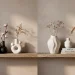 Minimalist winter shelf styled with a collection of abstract white ceramic sculptural vases in a warm modern living room.