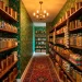 Wide view of a bold maximalist pantry with floral wallpaper, colorful jars, and brass lighting.