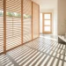 Minimalist entryway featuring a light oak wood slat screen with morning sunlight filtering through.