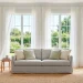 Bright sunlit summer living room featuring sheer white curtains, a light linen sofa, and an organic jute rug.