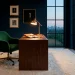 Luxurious home office with a dark walnut desk, emerald velvet chair, and moody navy blue walls in warm lighting.