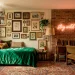 Wide horizontal view of a colorful maximalist dorm room with velvet bedding, plants, and neon wall art.