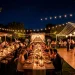 Wide horizontal shot of an enchanting backyard wedding reception under the stars with warm ambient lighting.