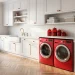 Wide shot of a modern laundry room with cherry red appliances and decor accents.