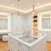 Wide view of a bright white windowless dressing room with gold accents and professional LED lighting.
