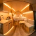 Sleek and modern Sprinter van interior layout with custom wood cabinetry and a functional galley kitchen.