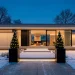 Modern minimalist house exterior decorated with elegant warm white holiday lighting and matte black planters.