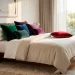 Luxurious king-sized bed with an assortment of colorful plush velvet throw pillows in a bright bedroom.