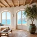 Wide view of a sun-drenched Mediterranean living room with white walls and rustic wooden beams.