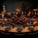 Moody Thanksgiving dining table with a foraged centerpiece of dark dried florals and tall black taper candles.