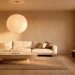Wide view of a serene Japandi living room featuring a low-profile linen sofa, stone table, and oversized paper lantern.