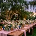 Wide horizontal banner of an ethereal garden wedding reception table under a canopy of twilight fairy lights.