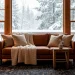A cozy winter lounge featuring a cognac leather sofa layered with cream flax linen throws and pillows.