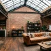 Wide view of an industrial attic apartment featuring exposed brick walls, metal beams, and a vintage leather sofa.