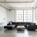 Wide industrial minimalist loft with copper and silver exposed pipes and white brick walls.