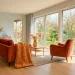 Wide shot of a modern spring living room with vibrant zesty orange accents and natural sunlight.