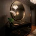 Glossy black lacquer cabinet in a moody entryway with brass accents and a round mirror.