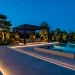Wide landscape of a modern garden with architectural lighting at night featuring warm LEDs.