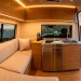 A modern, high-tech camper van interior featuring smart LED lighting, digital control panels, and sleek bamboo cabinetry at sunset.