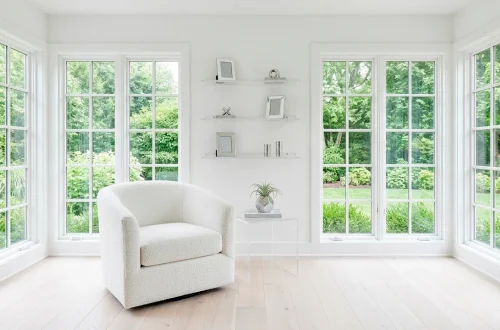 A small bright white sunroom with large windows and minimalist decor flooded with natural light.