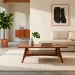 Minimalist living room featuring a sleek mid-century modern coffee table with wooden tapered legs on a cream rug.
