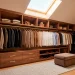 Luxurious attic wardrobe featuring rich wood cabinetry and brass hardware under slanted ceilings