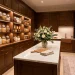 Luxurious walk-in pantry with dark oak cabinetry, brass hardware, marble island, and flawlessly organized glass storage jars.