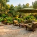Sun-drenched patio featuring outdoor furniture with olive green cushions and a matching shade umbrella.
