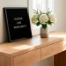 Modern oak entryway console table featuring a black felt letter board displaying a patriotic Memorial Day quote next to fresh hydrangeas.