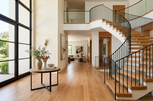 Beautiful modern foyer with oak staircase and sleek wrought iron railing blending seamlessly into a bright entryway.