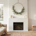 Minimalist brass hoop Christmas wreath hanging above a sleek marble fireplace in a modern living room.