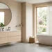 Wide view of a modern Scandinavian bathroom with a floating oak vanity, freestanding tub, and natural sunlight.