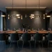 Wide view of a modern dining room featuring a sleek linear suspension statement chandelier over a wooden table