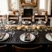 Sleek matte black cutlery set on a modern Thanksgiving table with white plates and autumn foliage.