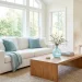 Bright living room featuring a white sofa decorated with refreshing spa blue throw pillows and elegant glass accents.