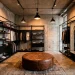 An industrial modern dressing room featuring exposed concrete walls, sleek black steel closets, and a leather ottoman.