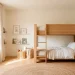 Bright and airy white shared kids bedroom featuring a modern natural wood bunk bed and brilliant natural light.