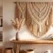 Wide boho entryway featuring a large textured macrame wall hanging above a wooden console table