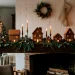 Minimalist earth-toned gingerbread village on a modern holiday mantel with cedar garland and brass candlesticks.