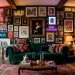 Eclectic maximalist living room gallery wall with clashing art styles over a dark velvet sofa