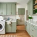 Beautifully refaced sage green laundry room cabinets with brass hardware and modern washer in a bright, clean space.