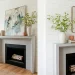Modern spring mantel decorated with asymmetrical leaning art pieces, fresh green branches, and elegant ceramics in a bright living room.