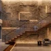Luxurious double height staircase featuring a floor-to-ceiling textured stone wall design.