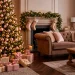 A beautifully decorated Christmas tree featuring blush pink and gold ornaments in a cozy, elegant living room.