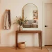 Cozy small modern entryway with a narrow wooden console table, arched mirror, and warm ambient lighting.