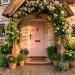 A beautiful pastel pink front door on a charming cottage framed by lush greenery and climbing roses.