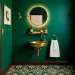 Stunning micro powder room with emerald walls and a space-saving brass sink.