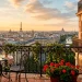 Panoramic view of a Parisian French balcony featuring a classic wrought iron bistro set at golden hour.