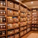 Perfectly organized deep pantry with clear bins and woven baskets on wooden shelves.
